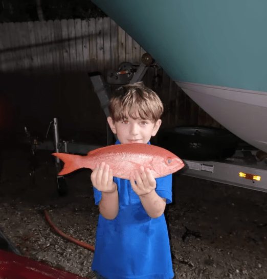 Young angler holding a vermilion snapper on a Rising Tide charter