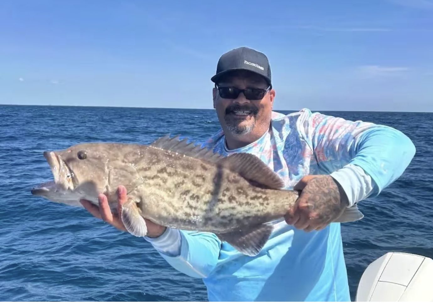 Angler holding a gag grouper caught on a Rising Tide charter
