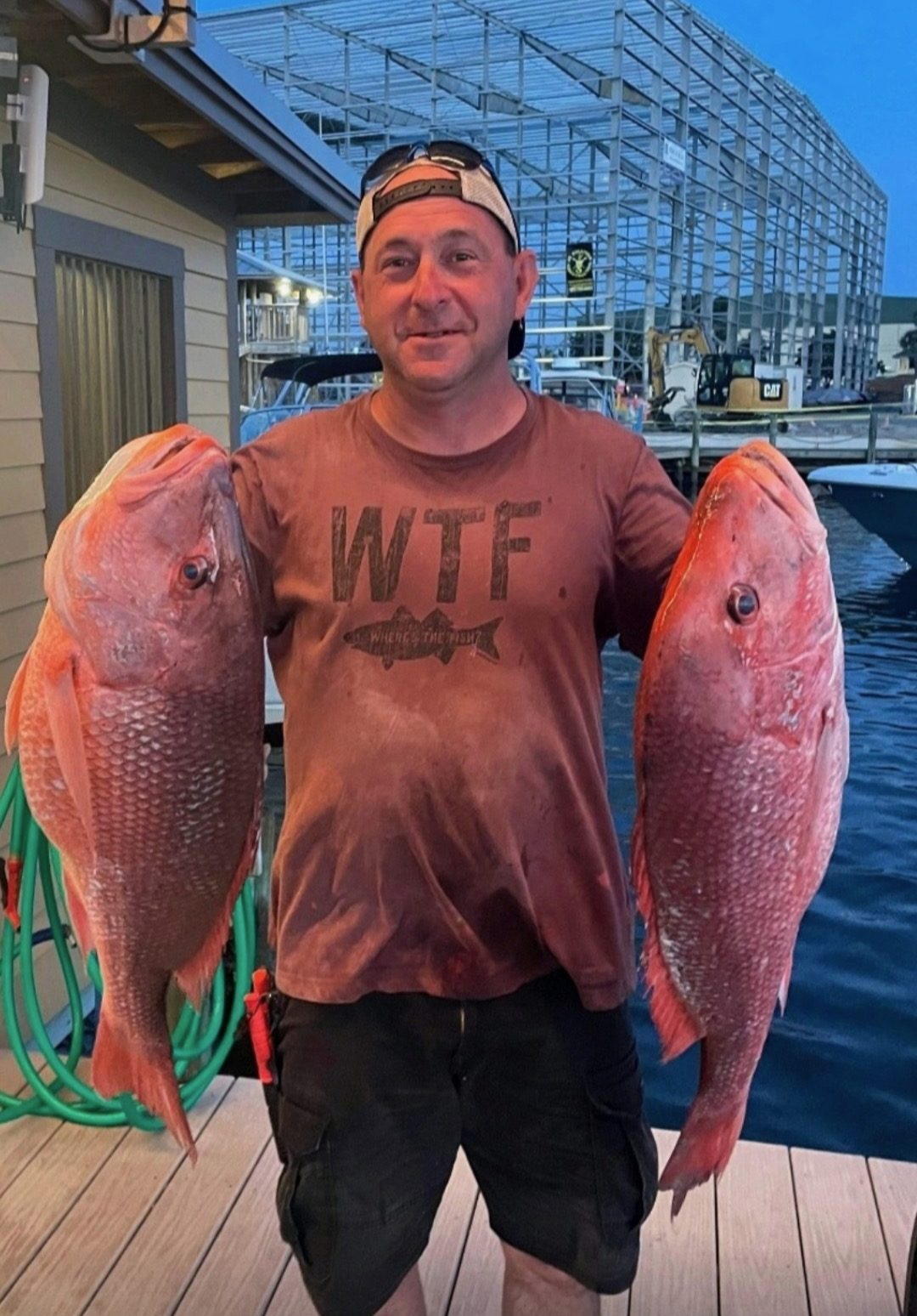 Angler holding two large red snapper, one in each hand