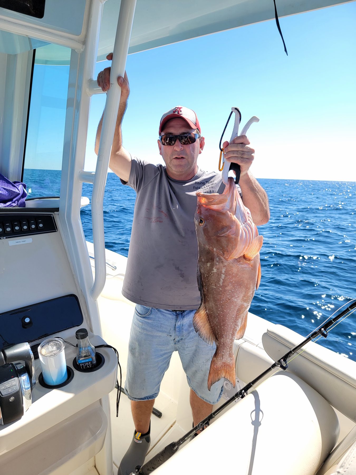 Angler with a red grouper on the deck of the charter boat